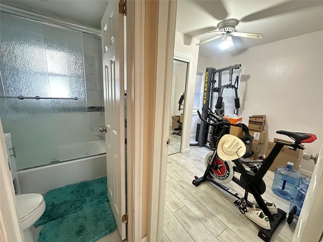 interior space featuring ceiling fan, shower / bath combination with glass door, and toilet