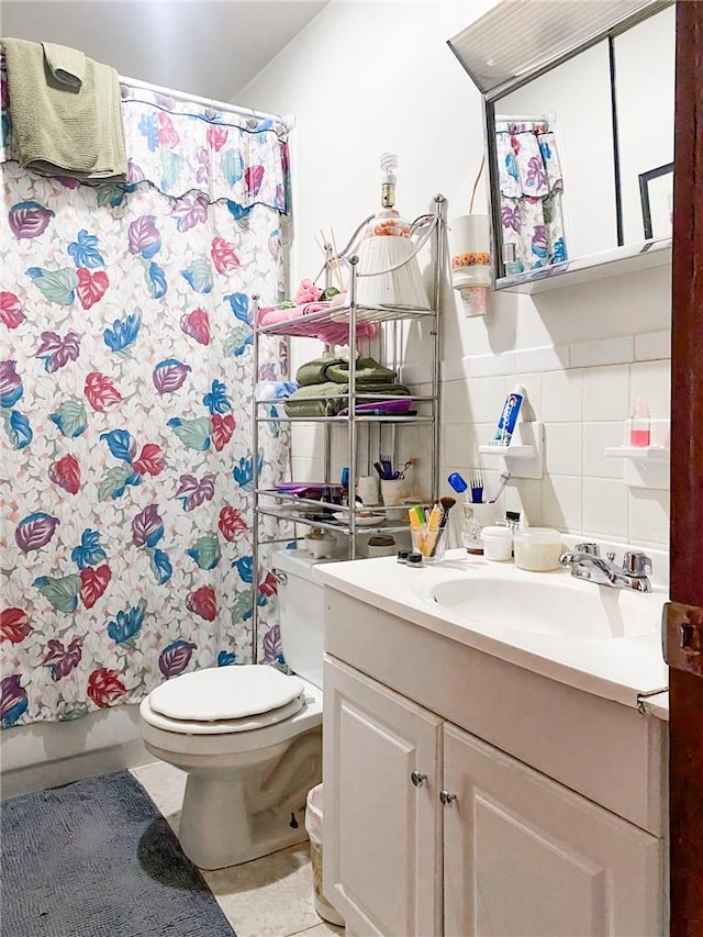 full bathroom with tile patterned flooring, toilet, shower / tub combo with curtain, vanity, and tile walls