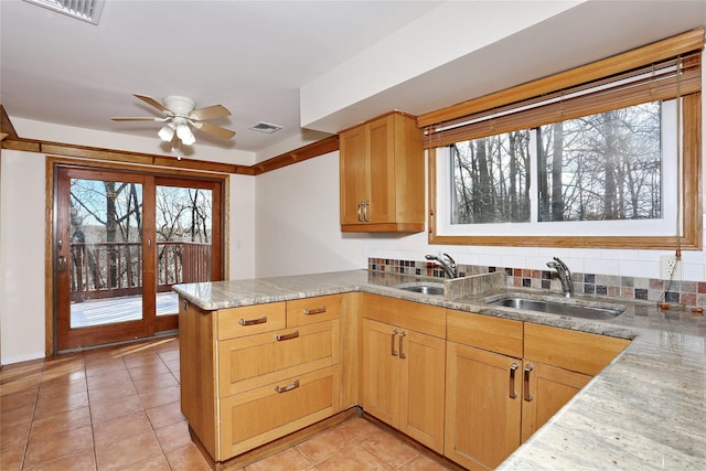 kitchen with kitchen peninsula, light tile patterned floors, ceiling fan, and sink