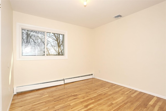 empty room featuring a baseboard radiator and light hardwood / wood-style floors