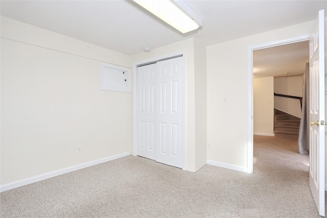 unfurnished bedroom with light colored carpet and a closet