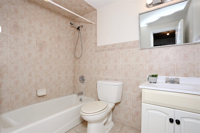 full bathroom with vanity, tile patterned floors, tiled shower / bath combo, toilet, and tile walls