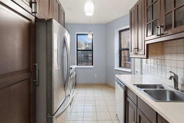 kitchen with sink, decorative backsplash, light tile patterned floors, appliances with stainless steel finishes, and decorative light fixtures