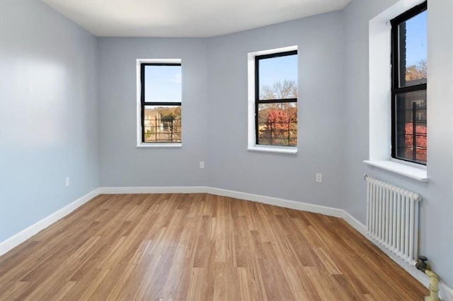 unfurnished room featuring radiator and light hardwood / wood-style floors