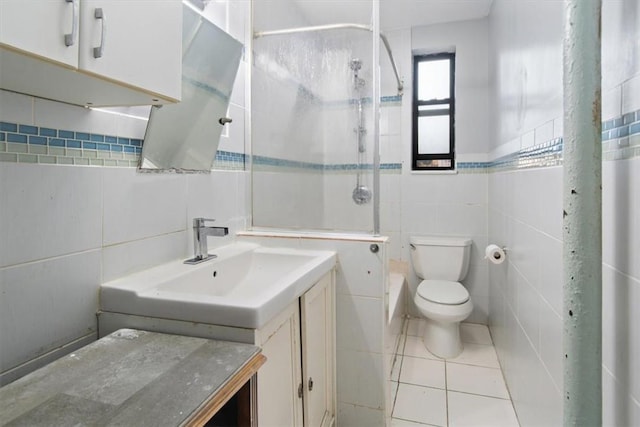 bathroom with a tile shower, tile patterned flooring, toilet, vanity, and tile walls