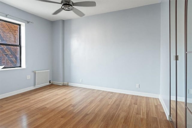 unfurnished room featuring ceiling fan, radiator heating unit, and light hardwood / wood-style floors