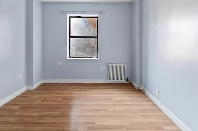 empty room with light hardwood / wood-style floors and radiator heating unit