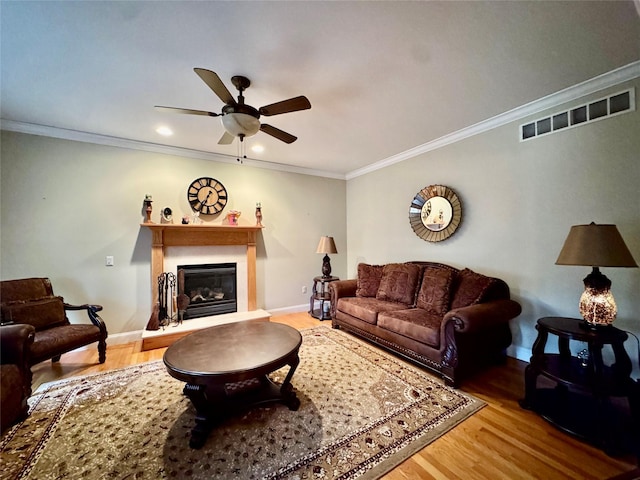 living room with hardwood / wood-style flooring, ceiling fan, and ornamental molding