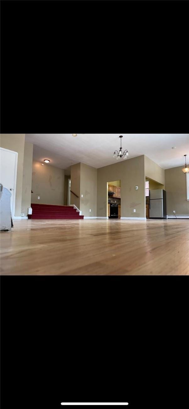 interior space featuring pendant lighting, stainless steel fridge, light wood-type flooring, and a chandelier