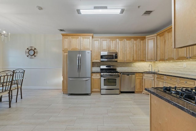 kitchen featuring sink, light brown cabinets, stainless steel appliances, tasteful backsplash, and a notable chandelier