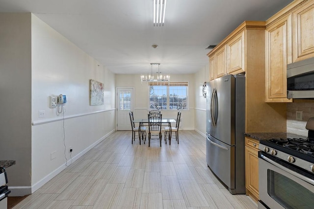 kitchen with light brown cabinets, stainless steel appliances, hanging light fixtures, and an inviting chandelier