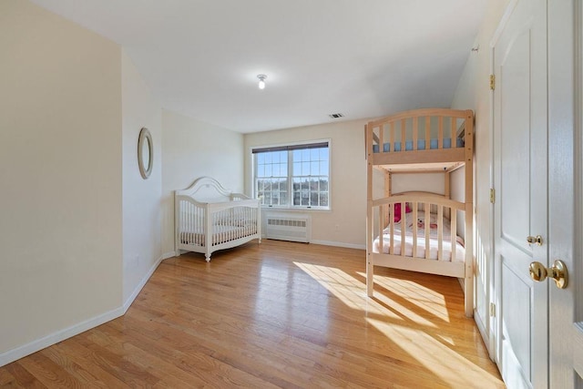 unfurnished bedroom featuring light hardwood / wood-style floors and radiator