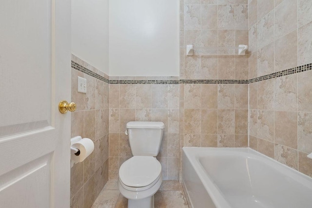 bathroom featuring tile patterned floors, a bathtub, toilet, and tile walls