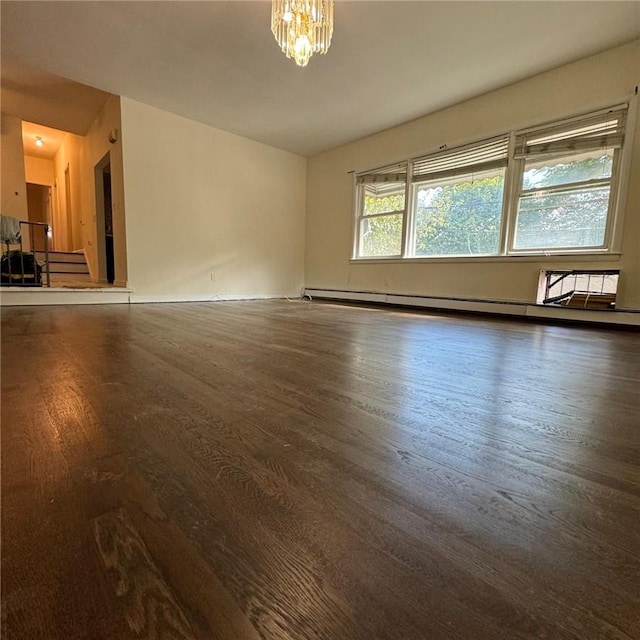 spare room featuring a baseboard radiator, dark hardwood / wood-style floors, and a notable chandelier