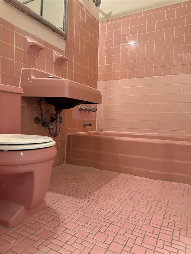 bathroom with toilet, tub / shower combination, and tile walls