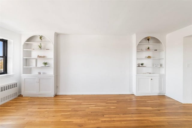 empty room featuring light hardwood / wood-style floors, radiator heating unit, and built in features