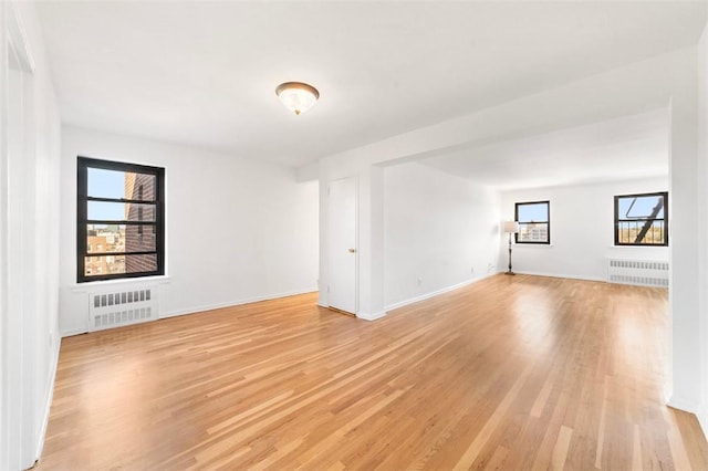 unfurnished room with radiator heating unit and light wood-type flooring