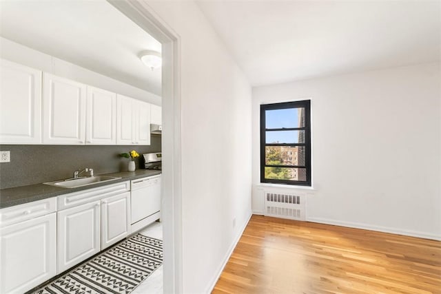 kitchen featuring sink, white cabinets, light wood-type flooring, and radiator heating unit