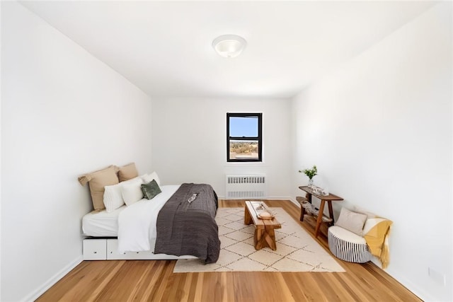 bedroom with radiator heating unit and hardwood / wood-style floors