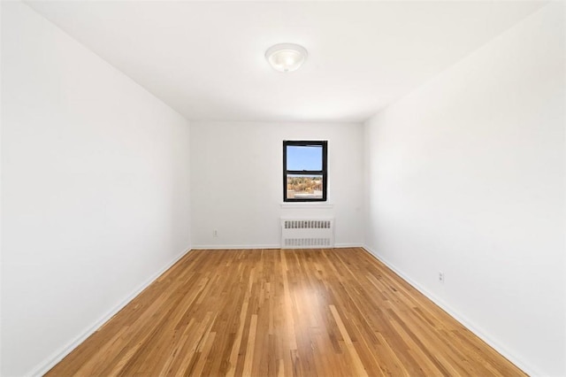 unfurnished room with radiator heating unit and light wood-type flooring