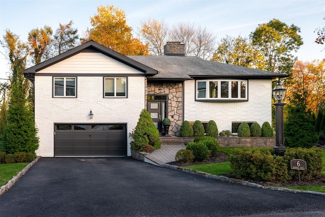 view of front of home featuring a garage, driveway, stone siding, a chimney, and brick siding