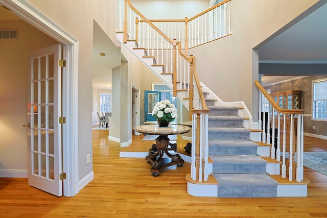 stairs with hardwood / wood-style floors, ornamental molding, and a high ceiling