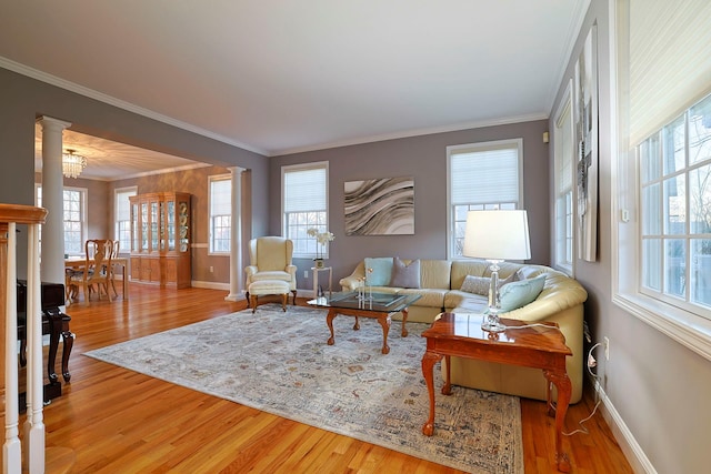 living room featuring wood-type flooring, ornate columns, and plenty of natural light