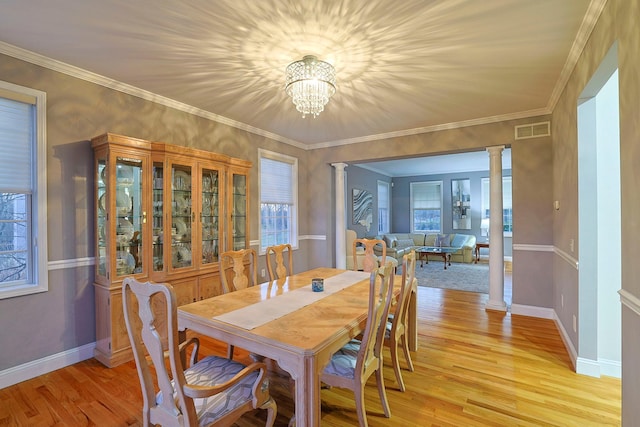 dining space featuring a notable chandelier, light hardwood / wood-style floors, a healthy amount of sunlight, and decorative columns