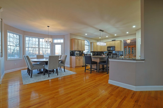 dining space with sink, an inviting chandelier, and light wood-type flooring