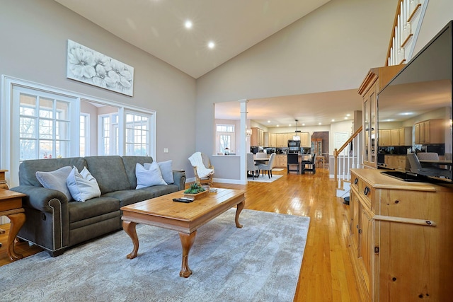 living room with ornate columns, high vaulted ceiling, and light hardwood / wood-style floors