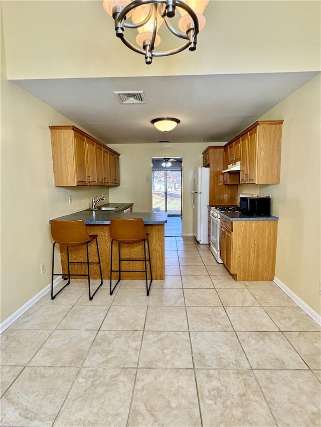 kitchen with white appliances, an inviting chandelier, sink, kitchen peninsula, and a breakfast bar area