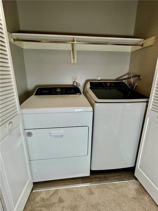 clothes washing area with light colored carpet and washing machine and clothes dryer