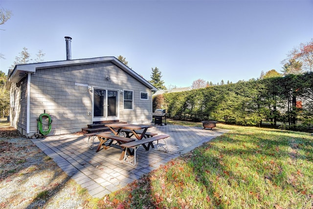 back of property with a yard, a fire pit, and a patio area