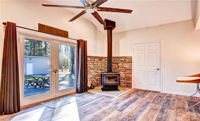 unfurnished living room with lofted ceiling, a wood stove, light hardwood / wood-style flooring, and french doors