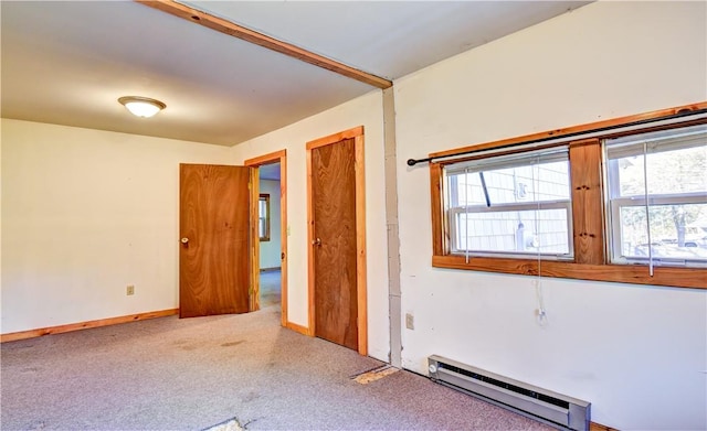 carpeted empty room with a baseboard heating unit