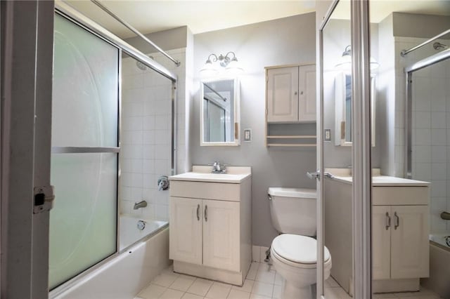 full bathroom with shower / bath combination with glass door, tile patterned flooring, vanity, and toilet