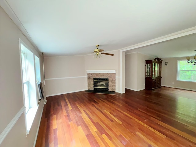 unfurnished living room with a fireplace, ceiling fan, ornamental molding, and dark wood-type flooring