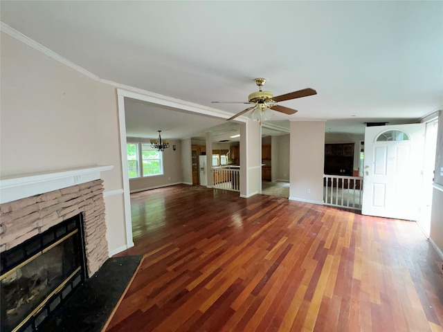 unfurnished living room featuring ceiling fan with notable chandelier, hardwood / wood-style flooring, a stone fireplace, and crown molding