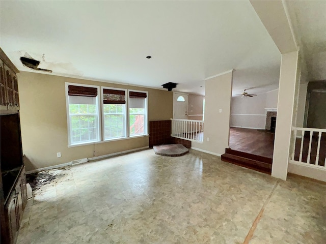 unfurnished living room with ceiling fan and a fireplace