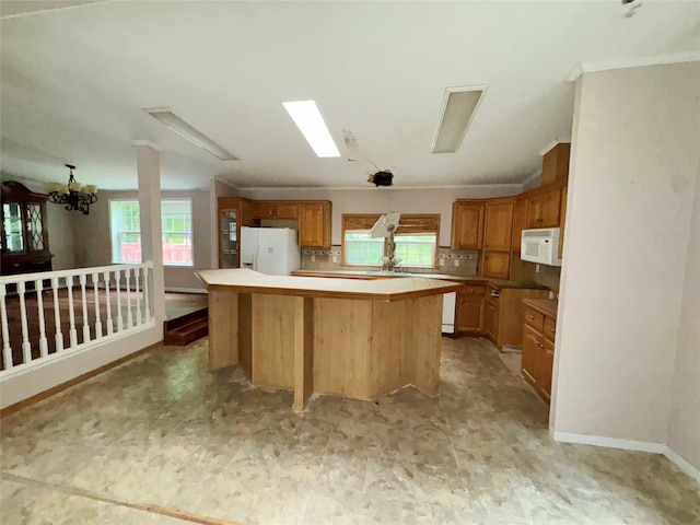 kitchen featuring backsplash, a center island, white appliances, and a notable chandelier