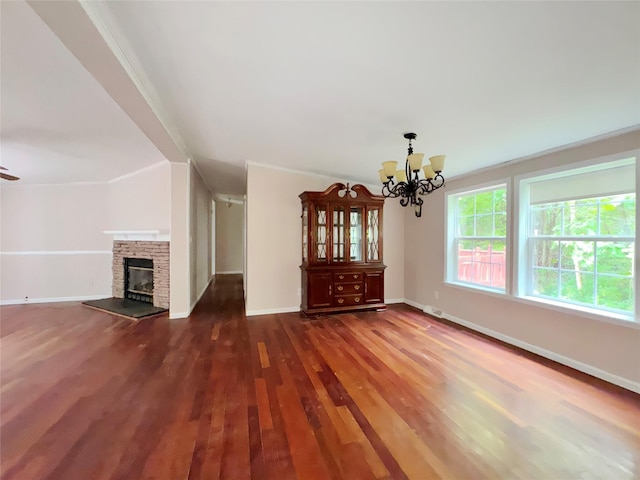 unfurnished living room featuring ornamental molding, an inviting chandelier, and dark wood-type flooring