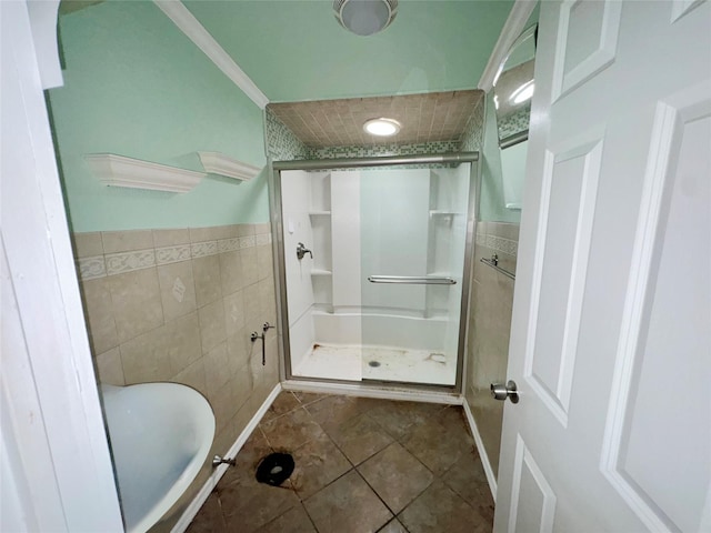 bathroom with tile patterned floors, tile walls, crown molding, and walk in shower