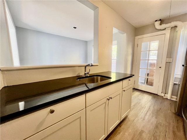 kitchen with light wood-type flooring, white cabinetry, and sink