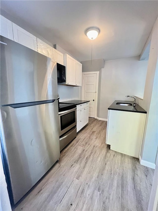 kitchen with sink, white cabinetry, stainless steel appliances, and light hardwood / wood-style flooring