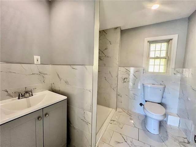 bathroom featuring walk in shower, vanity, tile walls, and toilet