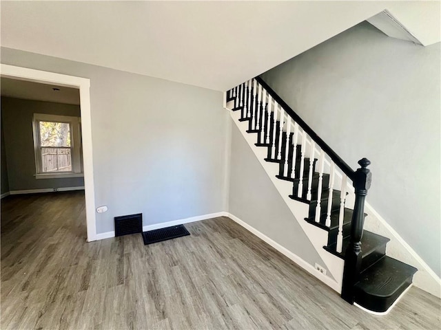 stairway with visible vents, baseboards, and wood finished floors