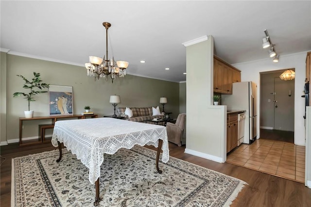 playroom featuring crown molding, rail lighting, dark wood-type flooring, and an inviting chandelier