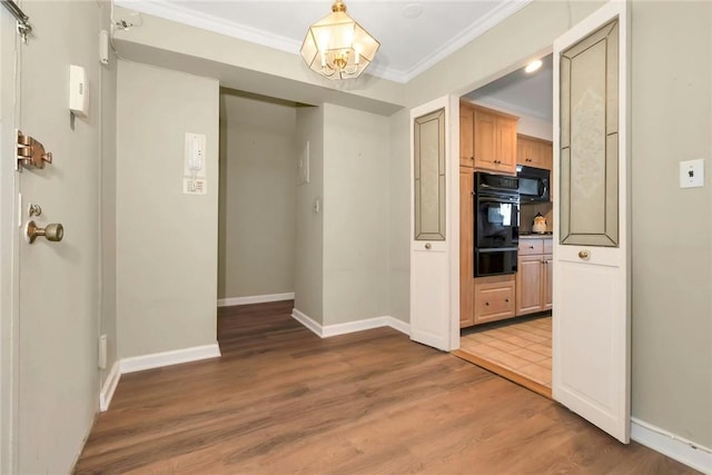 corridor featuring hardwood / wood-style floors, crown molding, and an inviting chandelier