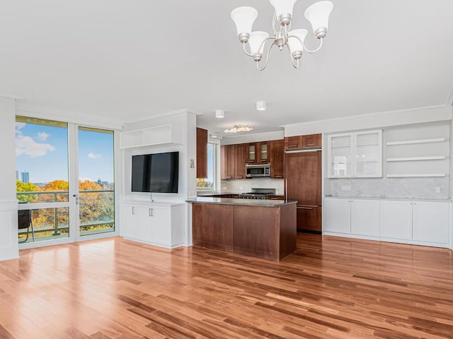 kitchen featuring appliances with stainless steel finishes, tasteful backsplash, a notable chandelier, light hardwood / wood-style floors, and hanging light fixtures