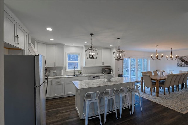 kitchen with appliances with stainless steel finishes, sink, decorative light fixtures, white cabinets, and a center island